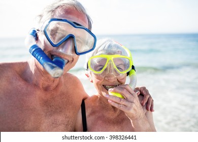 Portrait of happy senior couple with their diving mask at beach on a sunny day