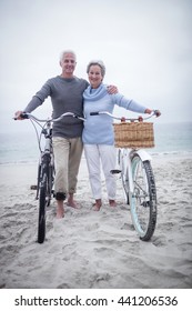 Portrait Of Happy Senior Couple With Their Bike On The Beach