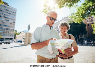 Portrait of happy senior couple using city map for finding their location. Mature couple travelling in a city with a road map. - Powered by Shutterstock