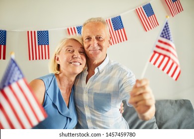 Portrait of happy senior couple waving American flag and smiling at camera - Powered by Shutterstock