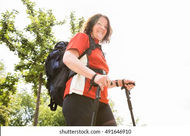 Portrait Of A Happy Senior Female Hiker With Hiking Pole