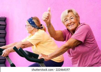 Portrait of happy Senior fitness woman doing thumbs up at spinning session in gym.