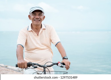 portrait of happy senior male riding a bicycle at the beach