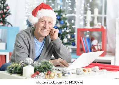 Portrait of happy senior man in Santa hat preparing for Christmas - Powered by Shutterstock