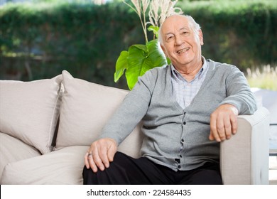 Portrait Of Happy Senior Man Sitting On Couch At Nursing Home Porch