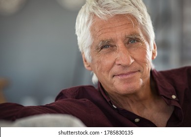 Portrait of happy senior man smiling at home. Old man relaxing on sofa and looking at camera with copy space. Close up face of elderly guy enjoying retirement. - Powered by Shutterstock