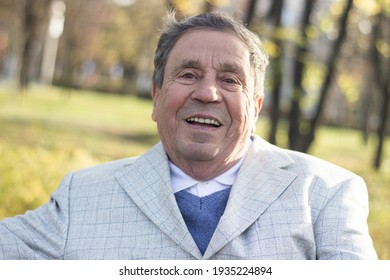 Portrait Of Happy Senior Man Smiling, In The Public Park, Outdoors. Old Man Relaxing Outdoors And Looking Away. Portrait Of Elderly Man Enjoying Retirement