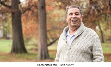 Portrait of happy senior man smiling, in the public park, outdoors. Old man relaxing outdoors and looking at camera. Portrait of elderly man enjoying retirement