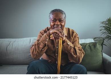 Portrait of happy senior man smiling at home while holding walking cane. Old man relaxing on sofa and looking at camera. Portrait of elderly man enjoying retirement.  - Shutterstock ID 2177445123
