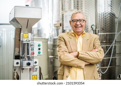 Portrait of happy senior man who owns winery. He is standing beside wine storage tanks. Industry wine making concept. - Powered by Shutterstock