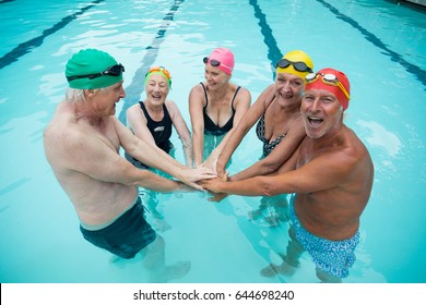 Portrait Of Happy Senior Swimmer Stacking Hands In Pool