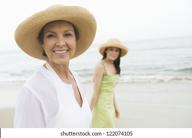 Portrait Of Happy Senior Woman And Daughter Walking At Beach