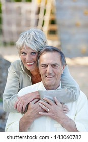 Portrait Of Happy Senior Woman Embracing Man From Behind At Park