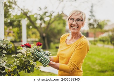 Portrait of happy senior woman gardening. She is pruning flowers. - Powered by Shutterstock