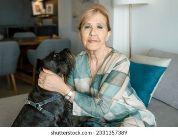 Portrait of happy senior woman hugging dog sitting on couch and enjoying retirement in living room - Powered by Shutterstock