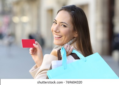 Portrait Of A Happy Shopper Holding Shopping Bags And Credit Card On The Street