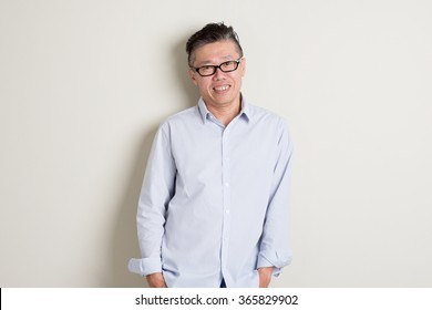 Portrait Of Happy Single Mature 50s Asian Man In Casual Business Smiling, Standing Over Plain Background With Shadow.