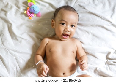 Portrait Of Happy Smile Asian Baby Boy Relaxing Looking At Camera.Cute Asian Newborn Child On The Bed At Home