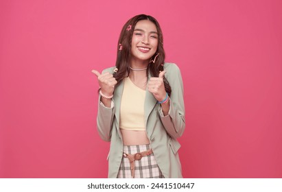 Portrait happy smile Asian teen woman shows thumb up isolated on pink background. - Powered by Shutterstock