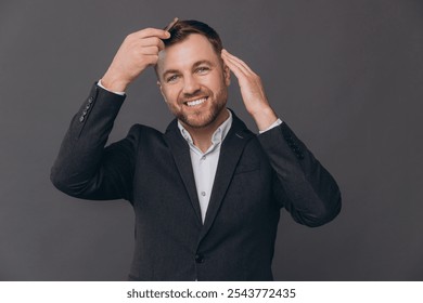 Portrait of happy smiling bearded businessman in grey suit combing his hair and beard looking at camera. Portrait over gray studio background with copy space. - Powered by Shutterstock