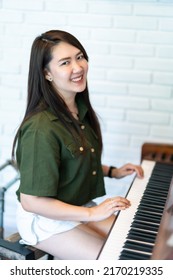 Portrait Happy Smiling beautiful Asian woman wearing brownish green dress stylish hipster with playing old wooden piano Vintage classic style.