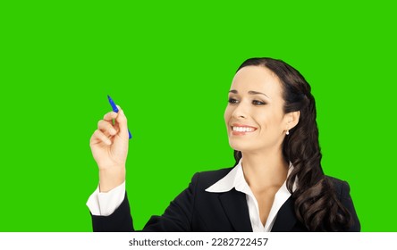 Portrait of happy smiling beautiful businesswoman in black confident suit, writing or drawing on screen, by marker. Brunette woman, isolated on green chroma key chromakey background. - Powered by Shutterstock