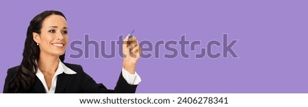 Portrait of happy smiling beautiful young businesswoman in black confident suit, writing or drawing something on screen, by marker. Brunette woman, isolated violet purple background