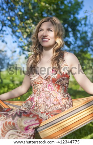 Portrait of Happy Smiling Blond Female Resting in Hummock in Spring Forest Outdoors.Vertical Image