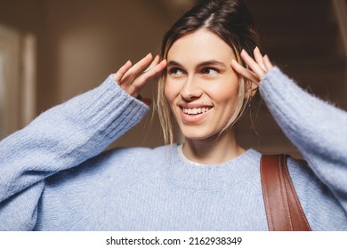 Portrait Of Happy Smiling Blonde Woman Exit Her Home She Go Away With Bag On Shoulder. Blonde Happy Woman With Low Bun Wear Blue Sweater. Young And Beautiful Girl Look At Side.