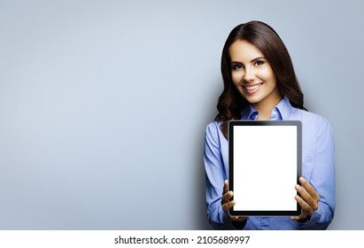 Portrait Of Happy Smiling Brunette Businesswoman Showing Mock Up Blank Tablet Pc, Ipad Touchpad With Copy Space Area, Isolated Over Grey Background. Confident Young Business Woman At Studio. Executive