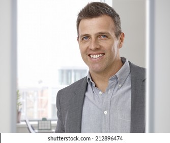 Portrait Of Happy Smiling Businessman At Office. Suit With No Tie, Looking At Camera.