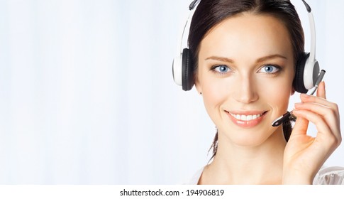 Portrait of happy smiling cheerful beautiful young support phone operator in headset, at office, with copyspace area