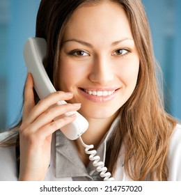 Portrait of happy smiling cheerful young female doctor on phone, at office - Shutterstock ID 214757020