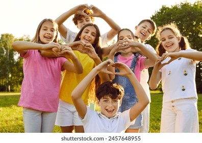 Portrait of a happy smiling children looking at the camera making heart shape gesture standing in the summer park outdoors. Thankful kids doing love sign by hands in nature in sunlight. - Powered by Shutterstock