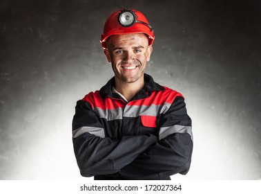 Portrait Of Happy Smiling Coal Miner With His Arms Crossed Against A Dark Background