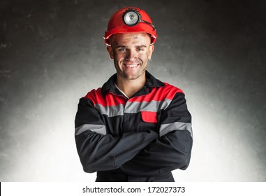 Portrait Of Happy Smiling Coal Miner With His Arms Crossed Against A Dark Background