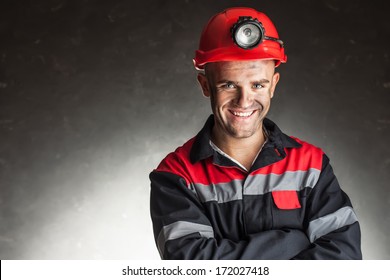 Portrait Of Happy Smiling Coal Miner With His Arms Crossed Against A Dark Background