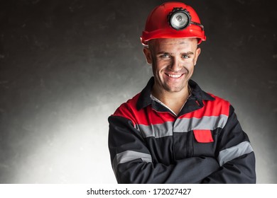 Portrait Of Happy Smiling Coal Miner With His Arms Crossed Against A Dark Background