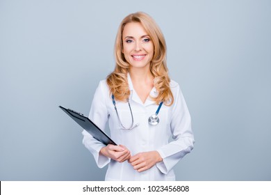 Portrait Of Happy Smiling Confident Glad Beautiful With Blonde Hair Female Family Doctor Wearing White Coat And Holding Clipboard, Isolated On Grey Background