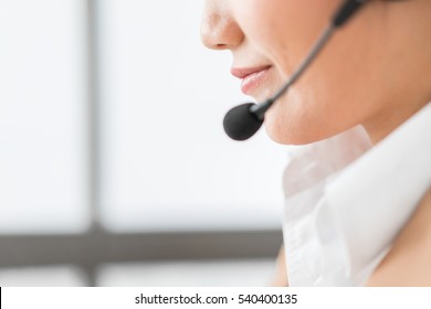 Portrait of happy smiling female customer support phone operator at workplace. Asian