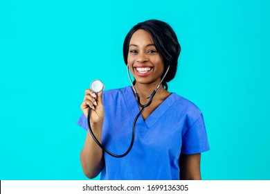 Portrait Of A Happy And Smiling Female Doctor Or Nurse Wearing Blue Scrubs Uniform Holding Stethoscope, Isolated On Blue Background