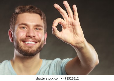 Portrait Of Happy Smiling Handsome Man Guy Giving Ok Okay Sign Gesture In Studio On Black.