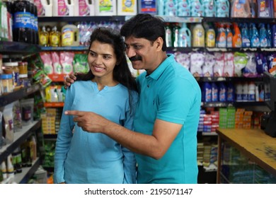 Portrait Of Happy And Smiling Indian Father And Daughter Purchasing In Grocery Store. Buying Grocery For Home In Supermarket. Cheerful Man Pointing Finger Towards Desired Product In Shopping Mart.