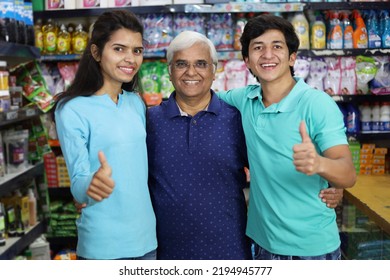 Portrait Of Happy And Smiling Indian Grand Father Purchasing In A Grocery Store With The Young Grand Children. Buying Grocery For Home In A Supermarket. Cheerful And Joyful Family Doing Thumbs Up.