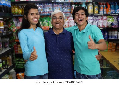 Portrait Of Happy And Smiling Indian Grand Father Purchasing In A Grocery Store With The Young Grand Children. Buying Grocery For Home In A Supermarket. Cheerful And Joyful Family Doing Thumbs Up.