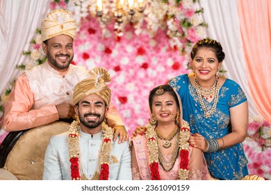 Portrait of Happy smiling Indian middle aged Father and Mother with newly wed daughter and son in law posing to camera on wedding stage - concept of family bonding, Marriage ceremony, parents - Powered by Shutterstock