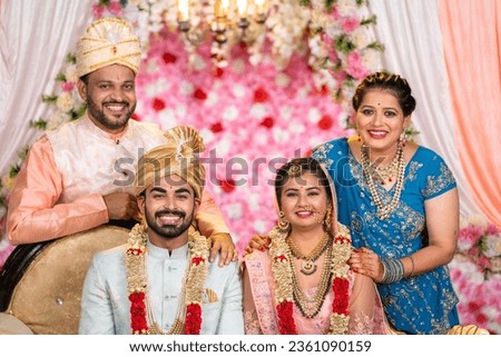 Portrait of Happy smiling Indian middle aged Father and Mother with newly wed daughter and son in law posing to camera on wedding stage - concept of family bonding, Marriage ceremony, parents