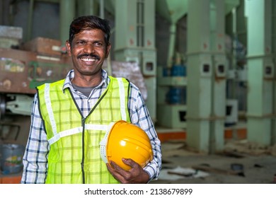 Portrait of happy smiling industrial worer with safety helmet in hand looking at with copy space - concept of safety measures, skilled labour and workforce.