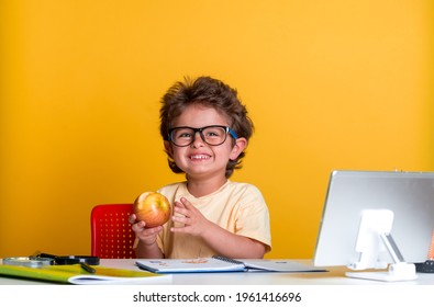 Portrait Of Happy Smiling Kid Boy Holding A Red Apple In The Classroom. School Child Has Lunch Box. Healthy Breakfast For Pupil. Snack In Bag With Fruits, Vegetables, And Water