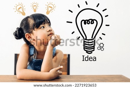 Portrait of happy smiling little child asian student girl having fun sit on table and looking at education thinking with lightbulb brainstorming creative idea.Back to school concept